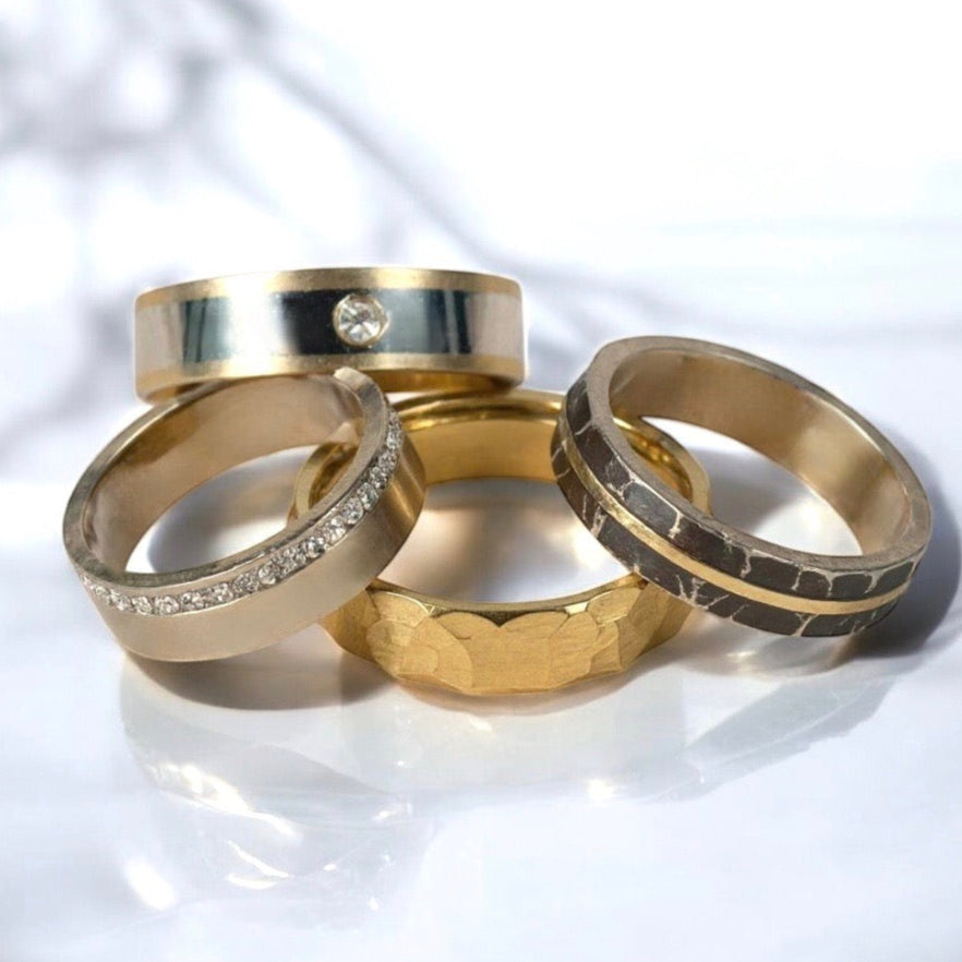 Four gold rings with different designs on a white background