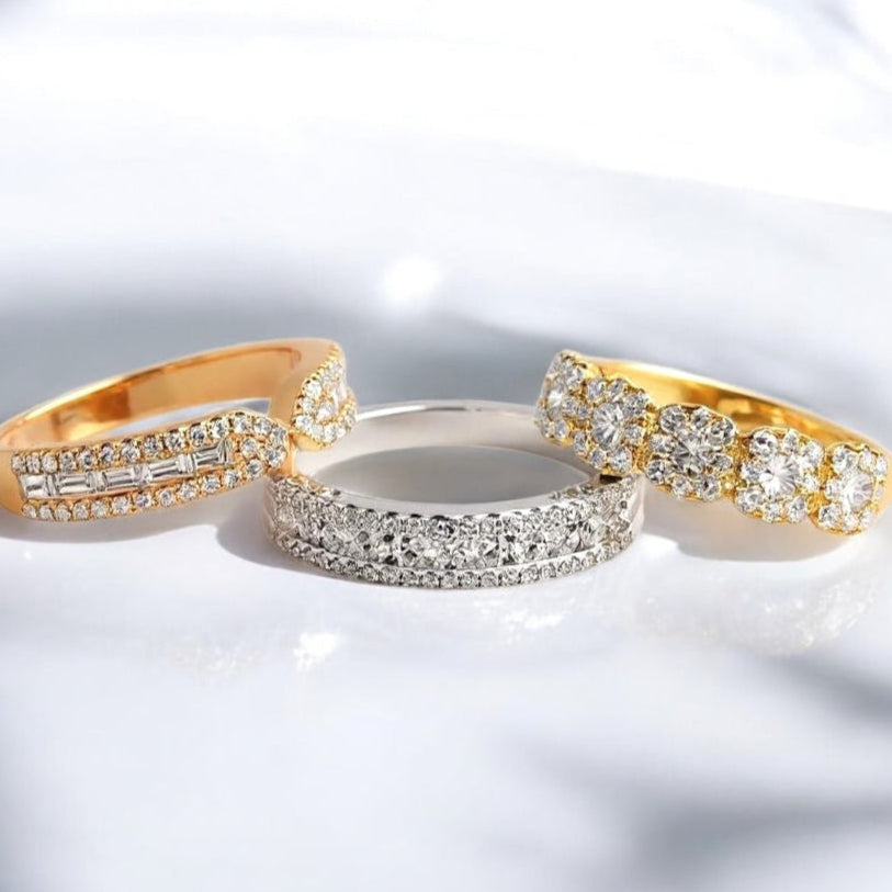 Three diamond rings in gold, silver, and rose gold on a white background